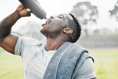 Buy stock photo Cropped shot of a handsome young male athlete drinking water while exercising outside