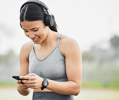 Buy stock photo Cropped shot of an attractive young female athlete checking her messages while exercising outside