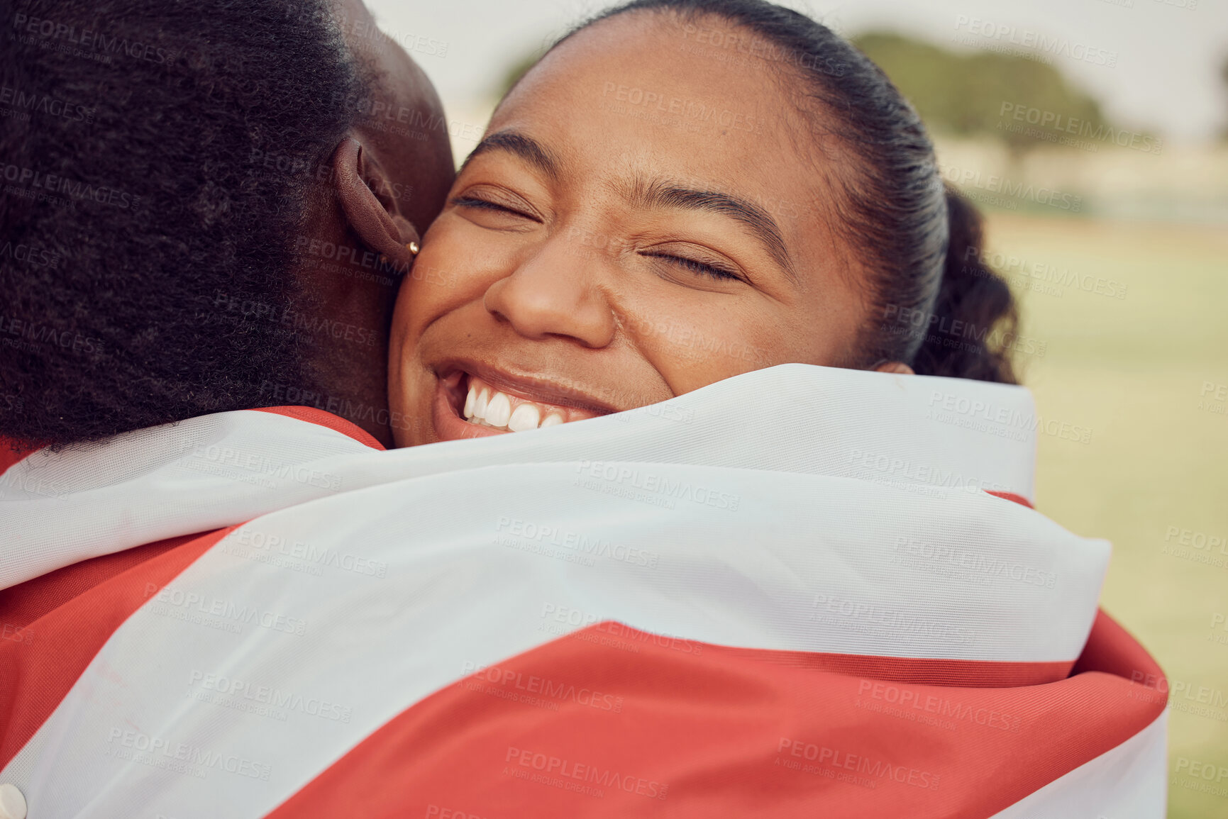 Buy stock photo Win, woman and hug on race track with smile, flag or support from team in USA. Girl athlete, competitive and happy on sports ground for victory, achievement and broken personal record or success