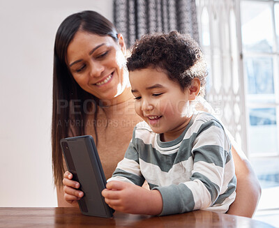 Buy stock photo Home, woman and toddler with phone by table for online education games, website and child development. Family, mother and son with technology in house for digital learning, entertainment or knowledge