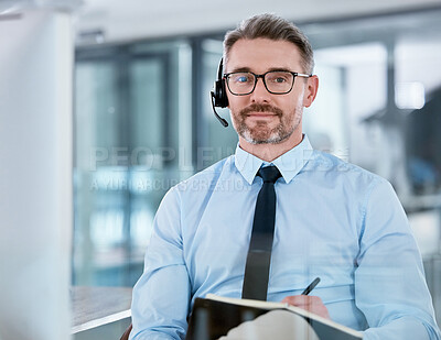 Buy stock photo Portrait of a mature call centre agent writing notes while working on a computer in an office