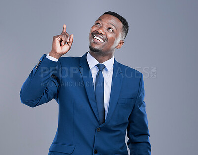 Buy stock photo Cropped shot of a handsome young businessman pointing upwards in studio against a grey background