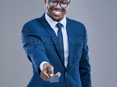 Buy stock photo Cropped shot of a handsome young businessman holding out his credit card in studio against a grey background
