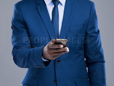 Buy stock photo Cropped shot of an unrecognizable businessman checking his text messages in studio against a grey background