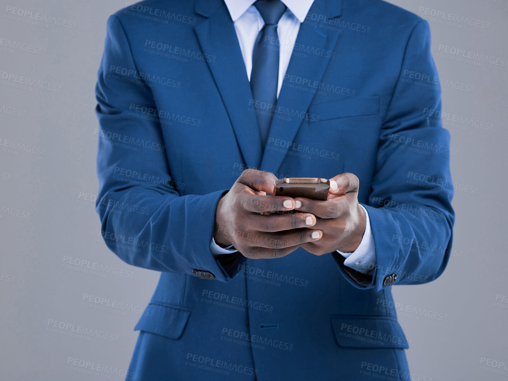 Buy stock photo Cropped shot of an unrecognizable businessman checking his text messages in studio against a grey background