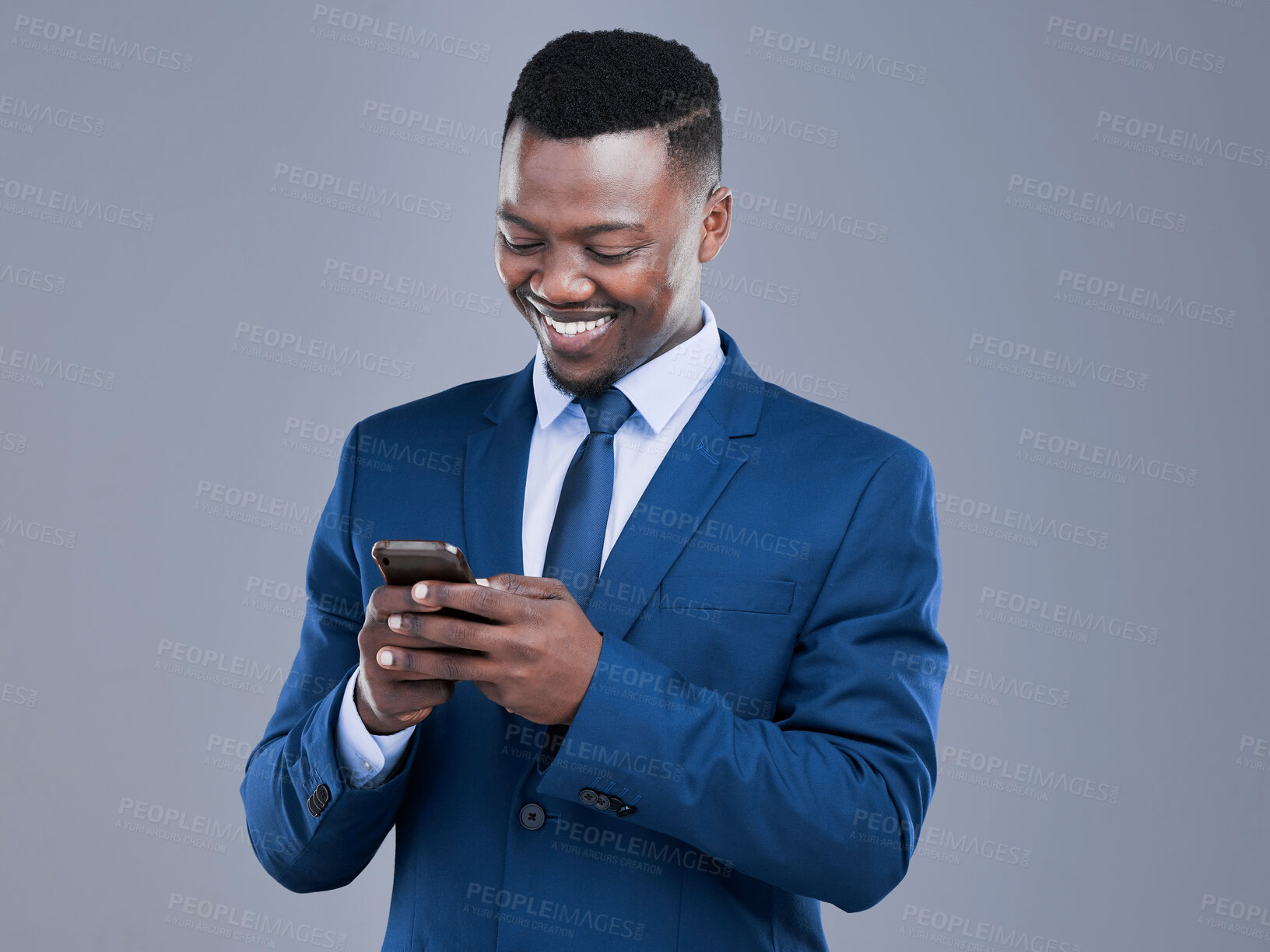 Buy stock photo Cropped shot of a handsome young businessman checking his text messages in studio against a grey background