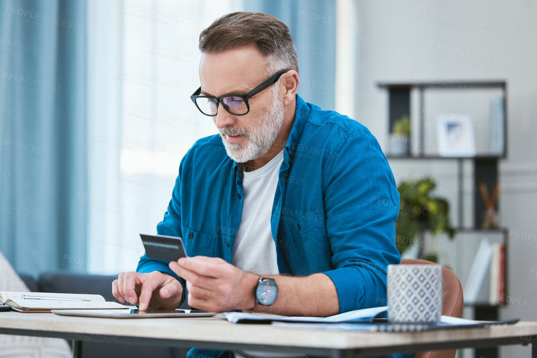 Buy stock photo Shot of a senior businessman using his digital tablet to make online card payments