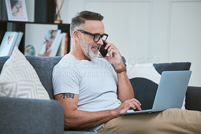 Buy stock photo Shot of a mature businessman using his laptop to work from home while making a phone call