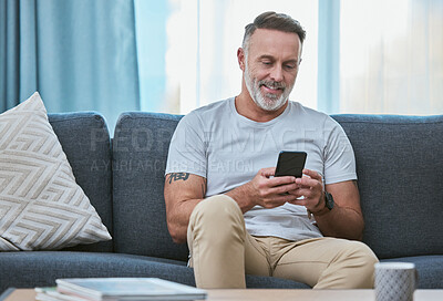 Buy stock photo Shot of a mature man relaxing at home while using his smartphone