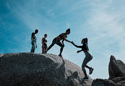 Buy stock photo Shot of a friend helping a woman onto a boulder on the beach