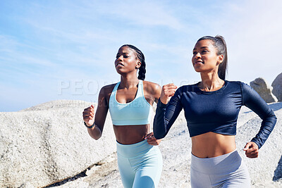 Buy stock photo Shot of two fit young women out for a run along the beach