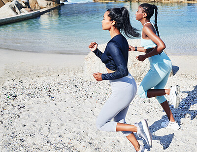 Buy stock photo Shot of two fit young women out for a run along the beach