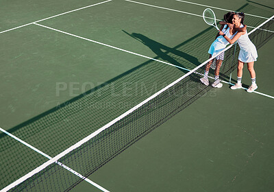 Buy stock photo Shot of two sporty young women hugging each other while playing tennis together on a court