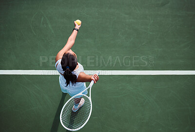 Buy stock photo High angle shot of a young woman serving a ball while playing tennis on a court