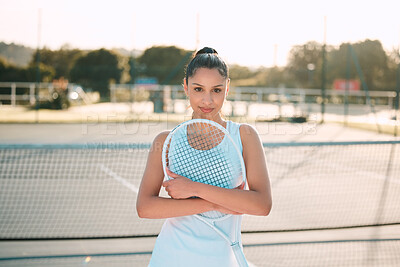 Buy stock photo Shot of an attractive young woman standing alone outside and posing with a tennis racket