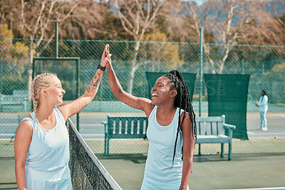 Buy stock photo Shot of a two young women standing and giving each other a high five after tennis practise