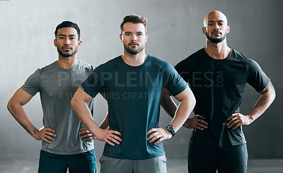 Buy stock photo Cropped portrait of a group of handsome young male athletes standing with their hands on their hips against a grey background