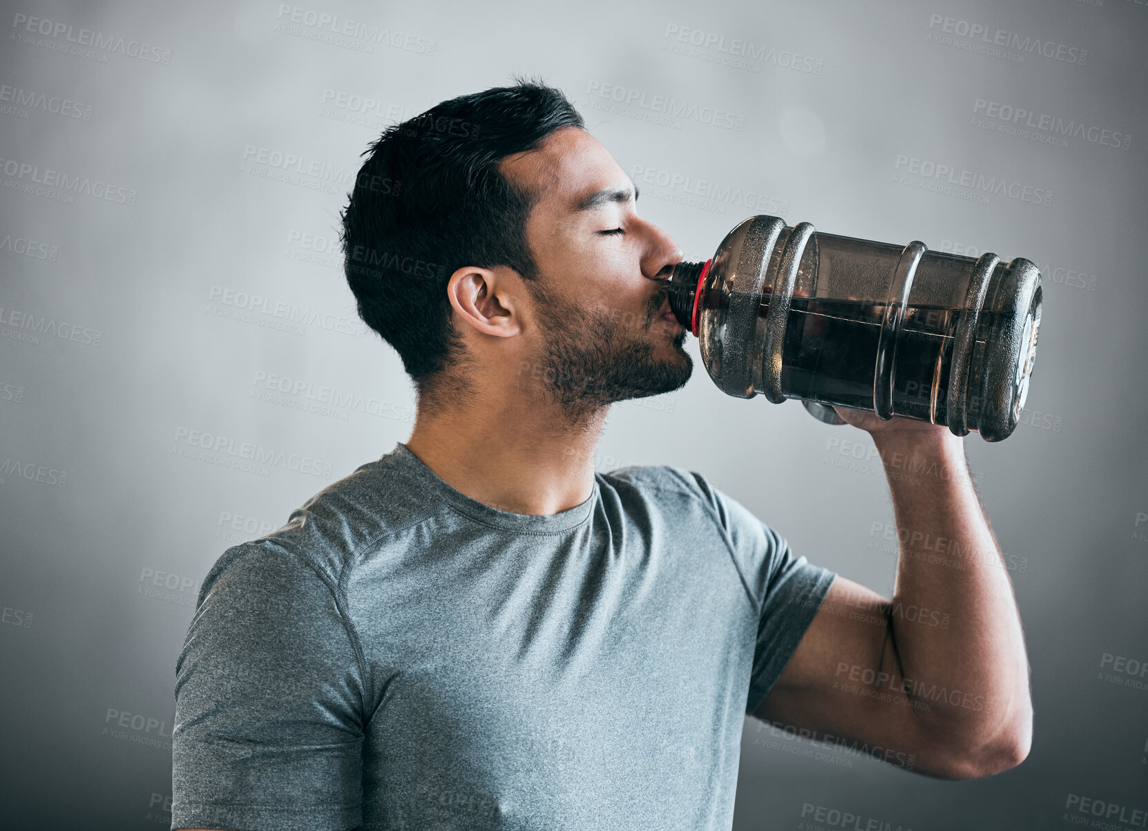 Buy stock photo Cropped shot of a handsome young male athlete drinking water against a grey background