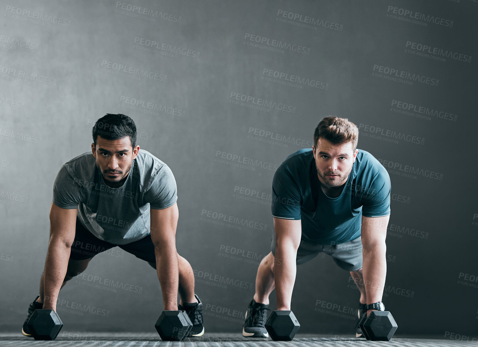 Buy stock photo Full length portrait of two handsome young male athletes working out with dumbbells side by side against a grey background