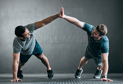 Buy stock photo Full length shot of two handsome young male athletes high fiving while doing pushups side by side against a grey background