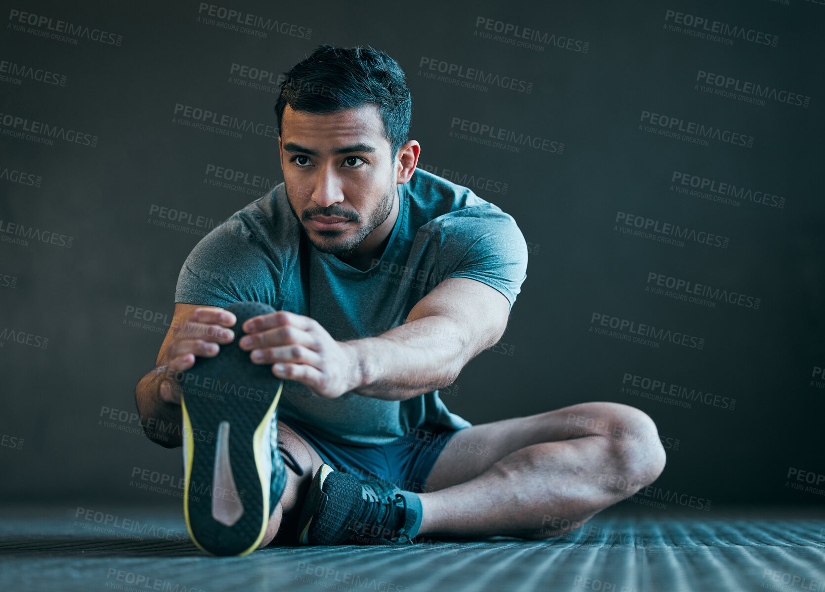 Buy stock photo Stretching, fitness and man on floor for exercise, training and warm up for athlete workout on gray background. Health, sports and person with leg muscles for wellness, performance and flexibility