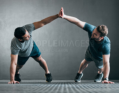 Buy stock photo Full length shot of two handsome young male athletes high fiving while doing pushups side by side against a grey background