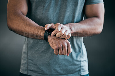 Buy stock photo Cropped shot of an unrecognizable young male athlete checking his smartwatch against a grey background