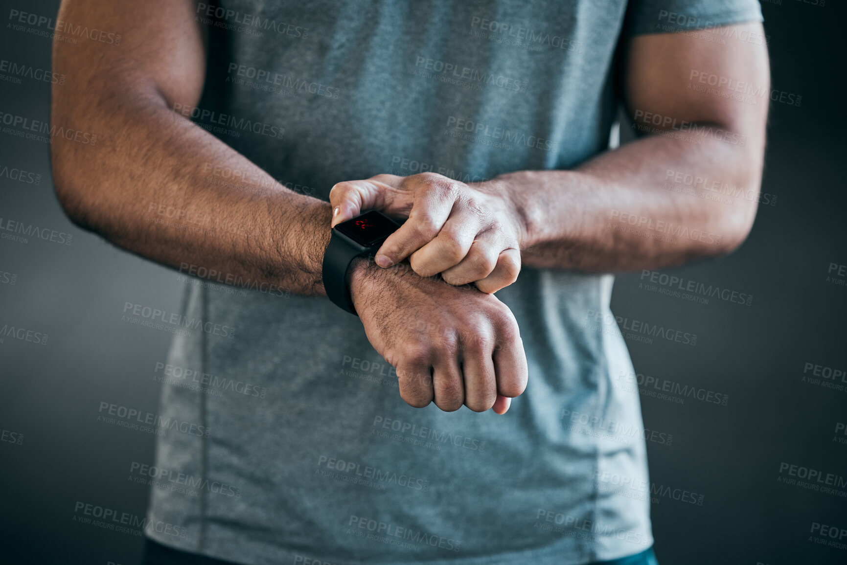 Buy stock photo Cropped shot of an unrecognizable young male athlete checking his smartwatch against a grey background