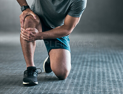 Buy stock photo Cropped shot of an unrecognizable young male athlete holding his knee in pain against a grey background