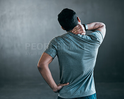 Buy stock photo Rearview shot of an unrecognizable young male athlete holding his neck in pain against a grey background