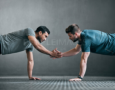 Buy stock photo Full length shot of two handsome young male athletes shaking hands while doing pushups face to face against a grey background