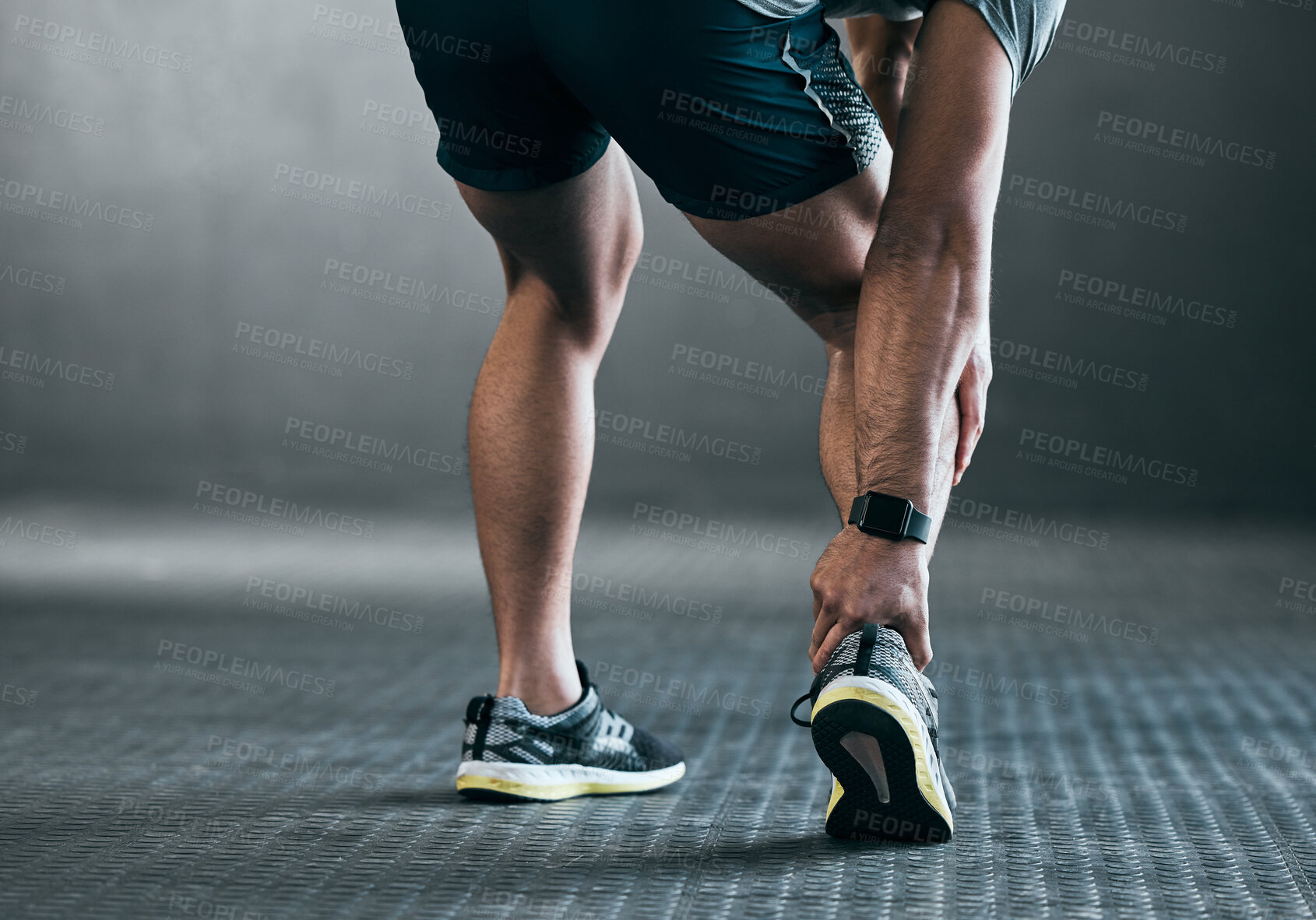Buy stock photo Rearview shot of an unrecognizable young male athlete holding his ankle in pain against a grey background