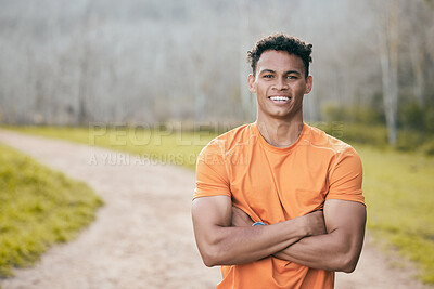 Buy stock photo Shot of a handsome young man standing alone outside with his arms folded during his workout