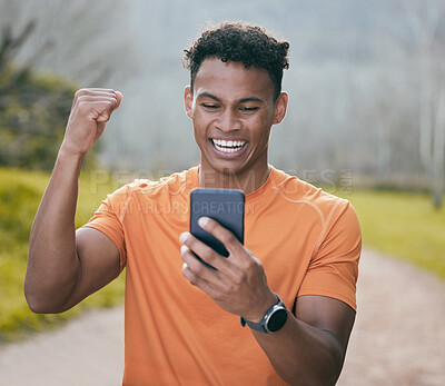 Buy stock photo Shot of a handsome young man standing alone outside and celebrating while using his cellphone after his workout