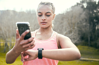 Buy stock photo Shot of an attractive young woman standing alone and using her cellphone while checking her watch during her outdoor workout