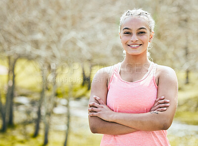 Buy stock photo Shot of an attractive young woman standing alone outside with her arms folded during her workout