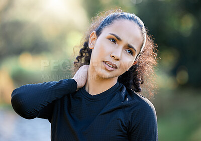 Buy stock photo Shot of a sporty young woman experiencing neck pain while exercising outdoors