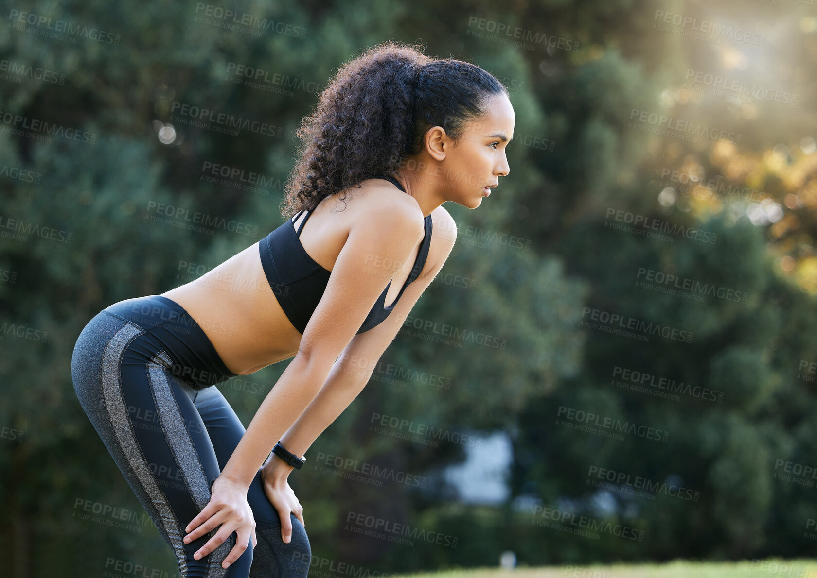 Buy stock photo Shot of a sporty young woman catching her breath while exercising outdoors