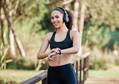 Buy stock photo Shot of a sporty young woman listening to music while exercising outdoors