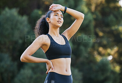 Buy stock photo Shot of a sporty young woman catching her breath while exercising outdoors