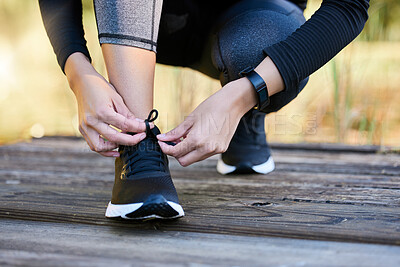 Buy stock photo Closeup shot of an unrecognisable woman tying her laces while exercising outdoors