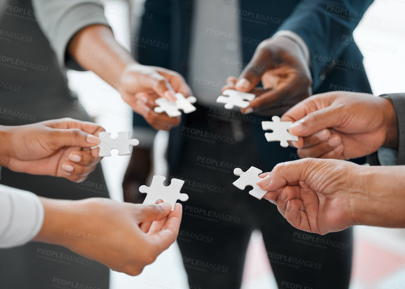 Buy stock photo Cropped shot of a group of unrecognizable businesspeople holding puzzle pieces while standing in the office