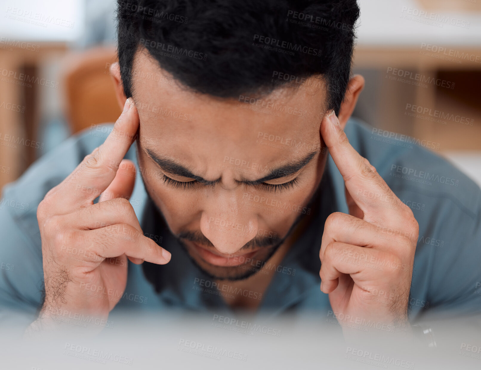 Buy stock photo Shot of a young businessman looking stressed out while working on a computer in an office