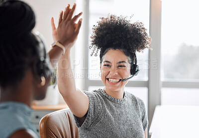 Buy stock photo Shot of two call centre agents giving each other a high five while working in an office