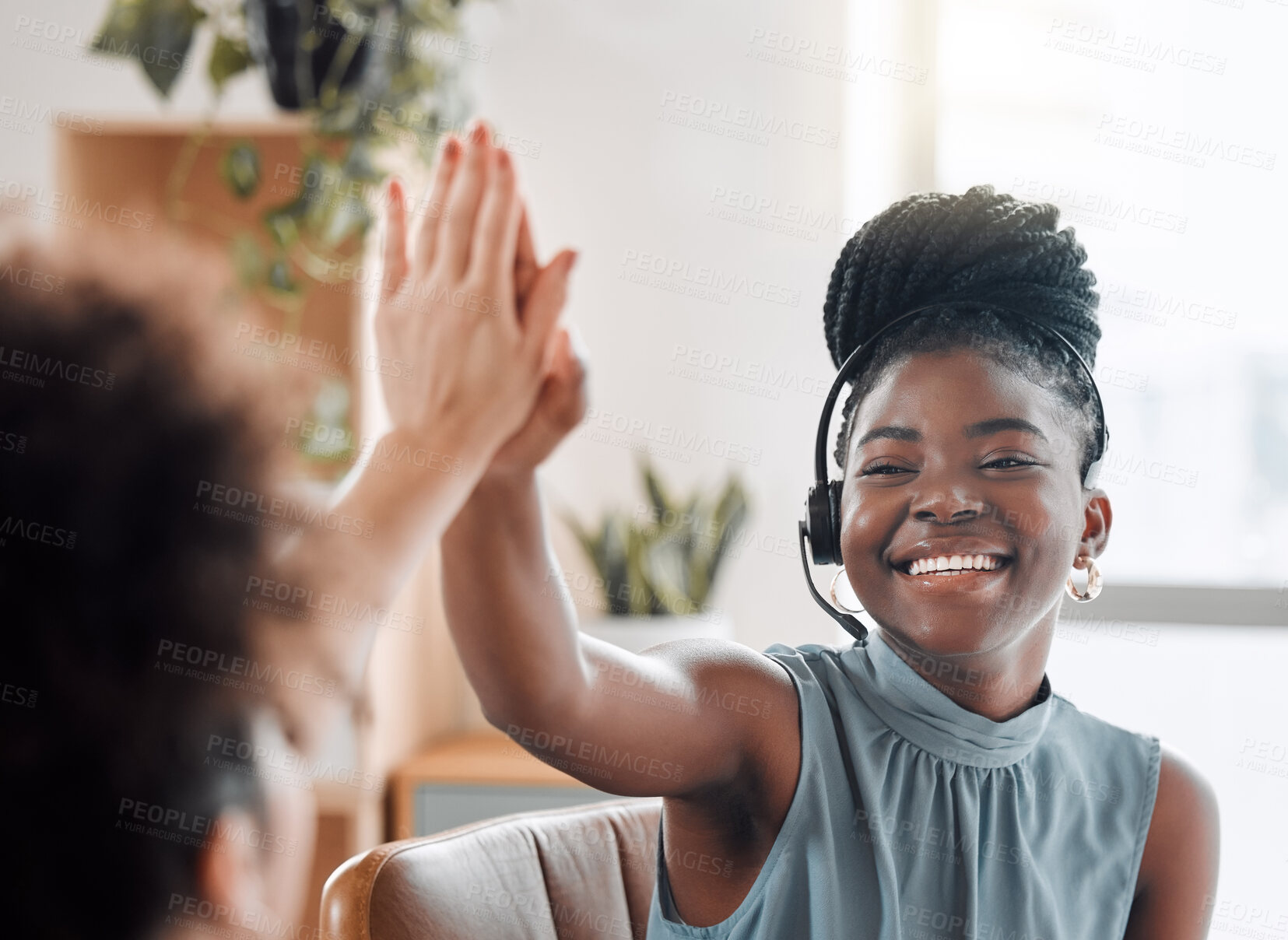 Buy stock photo Shot of two call centre agents giving each other a high five while working in an office