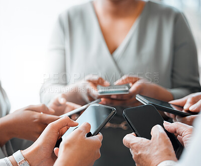 Buy stock photo Cropped shot of a group of unrecognizable businesspeople holding their cellphones while standing in the office