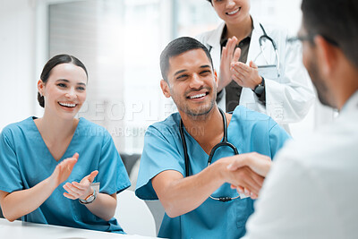 Buy stock photo Shot of a young male doctor shaking hands with a colleague at work