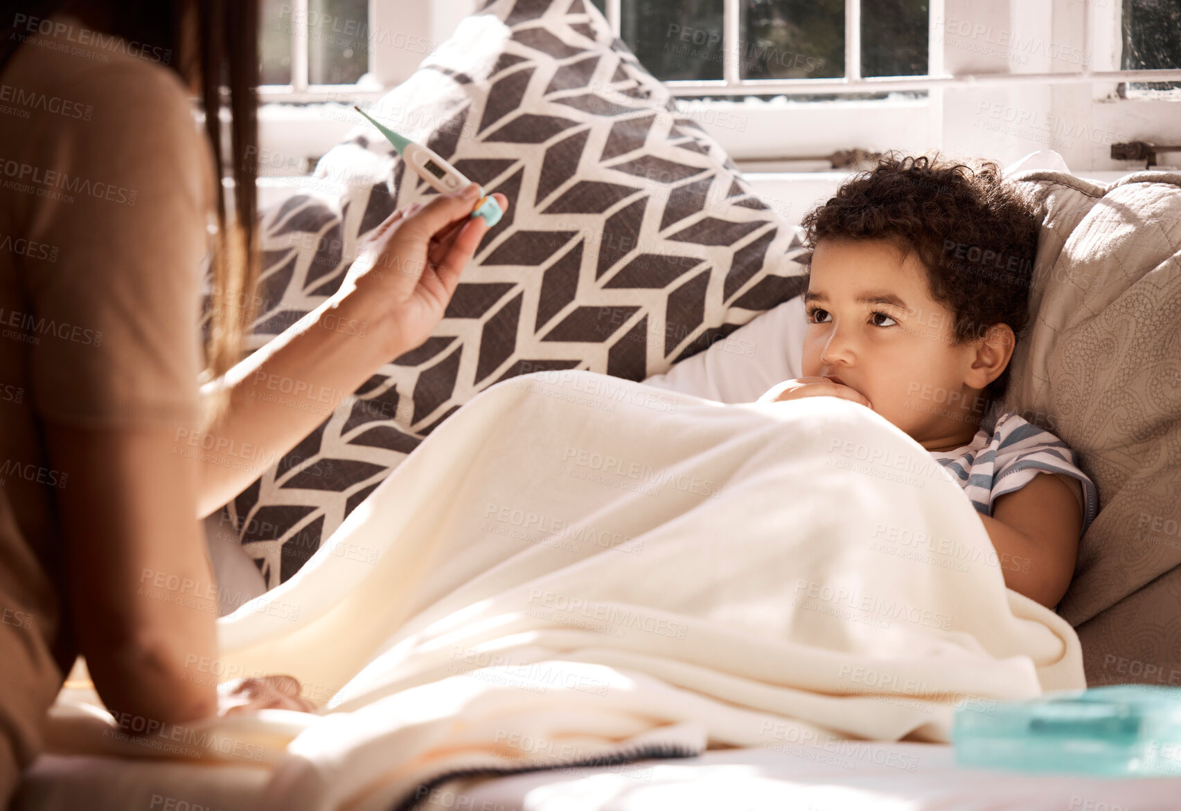 Buy stock photo Shot of a young mother checking her sick son's temperature at home