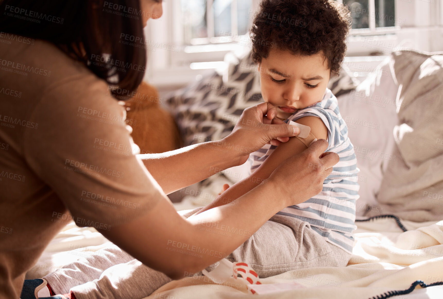Buy stock photo Mother, child and bandage on arm with injury for wound treatment, helping and care for bruise on bed in home. First aid, woman and apply adhesive plaster on son in bedroom with accident and support