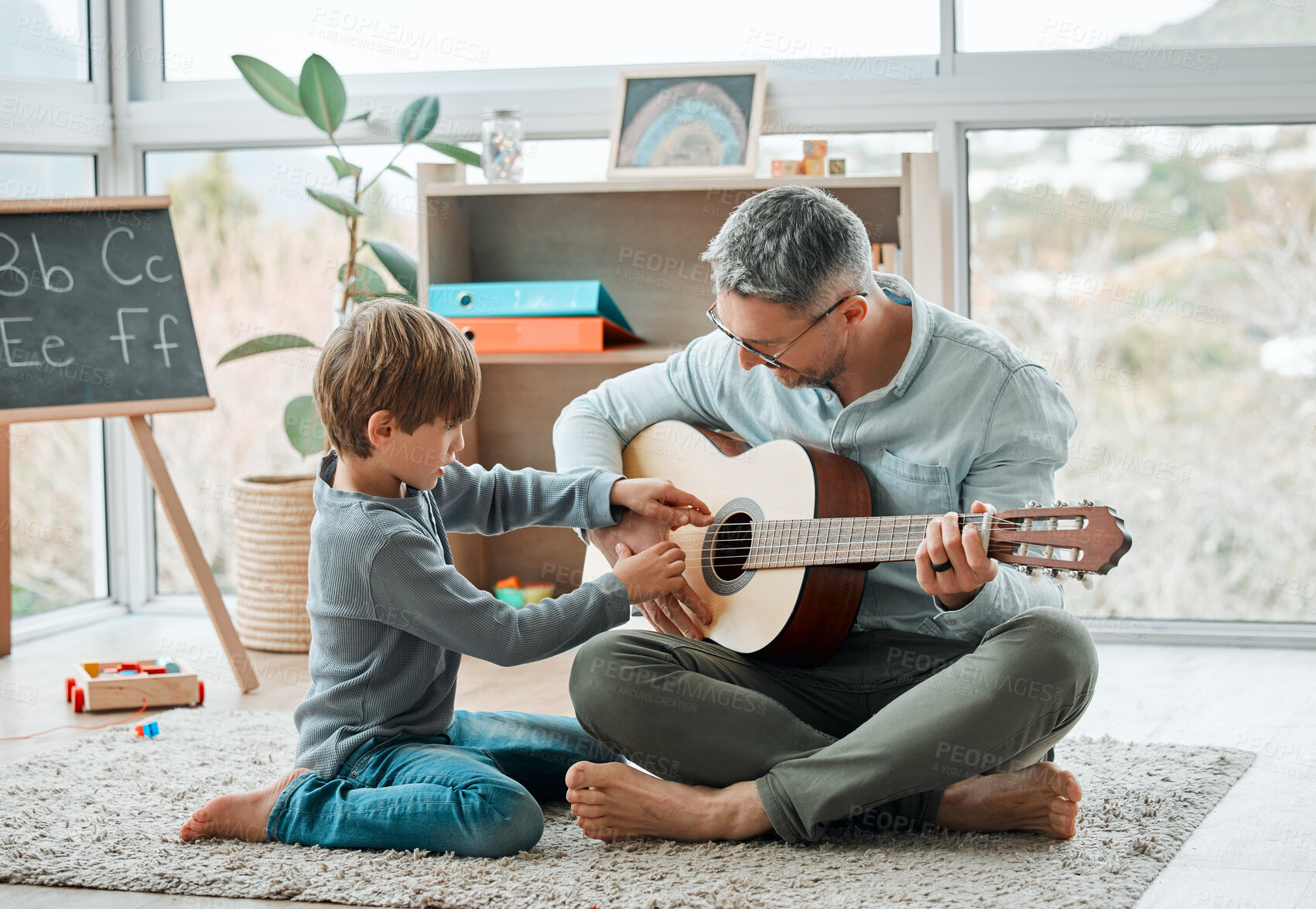 Buy stock photo Education, guitar and father teaching son how to play instrument on floor in living room of home. Family, lesson or music with single parent man and boy child in apartment for learning or study